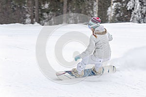 Young woman snowboarder in motion on snowboard in mountains