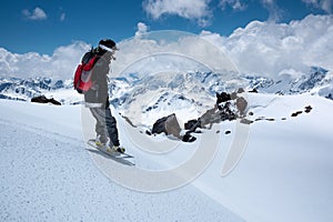 Young woman snowboarder stands on a snowboard on the slope getting ready to roll freeride backcountry down on a sunny