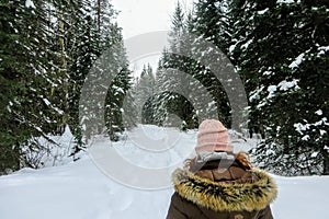 A young woman snowshoeing through the forests of Fernie Mountain Provincial Park, British Columbia, Canada