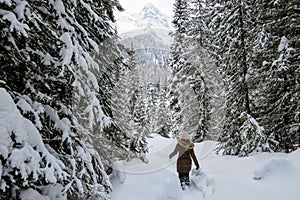 A young woman snowshoeing through forests of Island Lake in Fernie, British Columbia, Canada. A majestic winter background