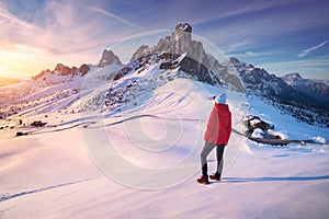 Young woman in snowy mountains at sunset in winter. Landscape