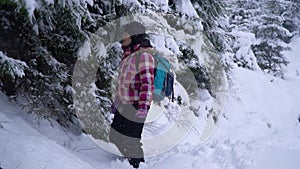 Young woman in the snowy woods. Young pretty tourist stands alone in the forest and looks around. She got lost. She is