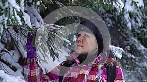 Young woman in the snowy woods. Young pretty tourist stands alone in the forest and looks around. She looks at snow and