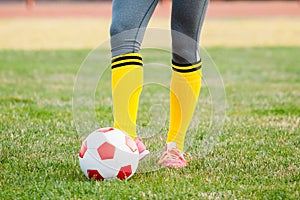 Young woman soccer player kicks ball on football field