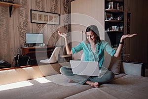 Young woman on sofa happily working on new project with laptop in home