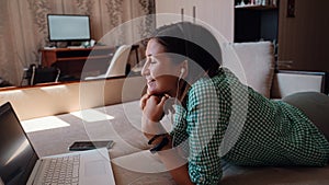 Young woman on sofa happily working on new project with laptop in home