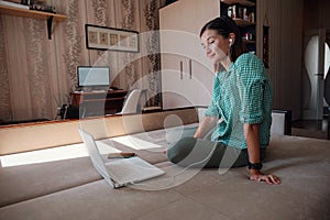 Young woman on sofa happily working on new project with laptop in home