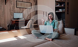 Young woman on sofa happily working on new project with laptop in home