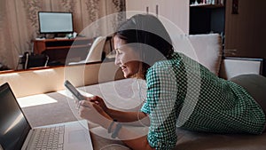 Young woman on sofa happily working on new project with laptop in home