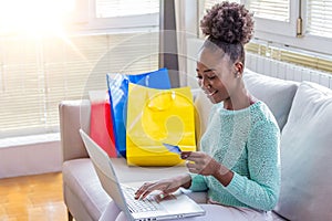 Young Woman On Sofa Shopping Online With Laptop. Young black woman inputting card information while shopping online. Online