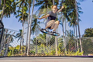 Young woman on a soft board for a trampoline jumping on an outdoor trampoline, against the backdrop of palm trees. The