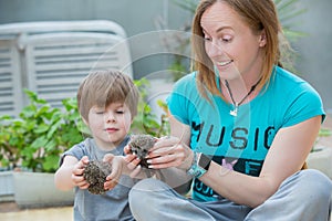 Young woman with son playing with hedgehog baby