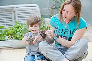 Young woman with son playing with hedgehog baby