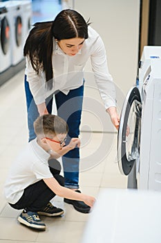A young woman with son in a store chooses a washing machine.. The concept of shopping.