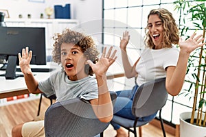 Young woman and son waiting at doctor appointment celebrating victory with happy smile and winner expression with raised hands