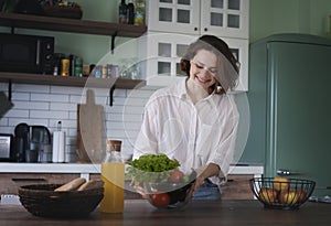 Young Woman sorting green fresh vegetables from shopping bag while standing in kitchen at home