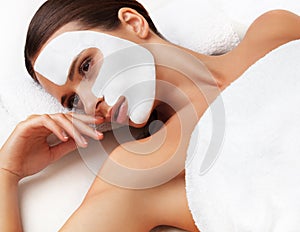 Young woman at spa salon with cosmetic mask on face. photo