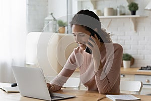 Young woman specialist sit by laptop give consultation using cell