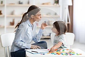 Young woman speech therapist teaching little boy with pronounciation deffects to say sound U during training