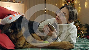 Young woman spend Christmas holidays at home with her pet on the bed with phone. Comfort, home, holidays