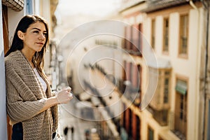 Young woman spending free time home.Self care,staying home.Enjoying view from the balcony.Quarantined person indoors.Serene