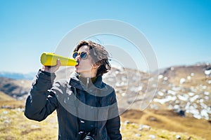 Young woman spending free time in national park/mountains.Hiking outdoor experience.Drinking from reusable vacuum insulated water