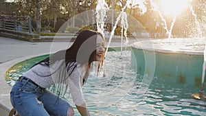 Young woman splashing water from fountain