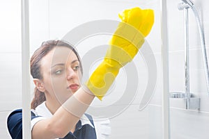 Young woman sponging down a shower cubicle