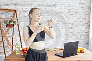 Young woman with spoon in her hands and in fitness clothes having healthy breakfast at home