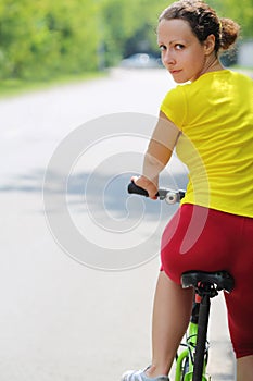 Young woman in sport clothes sits on bicycle and