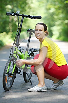 Young woman in sport clothes sits near bike and