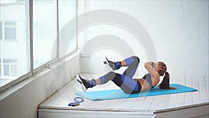 Young woman in a sport suit strengthens the muscles of the press in the club