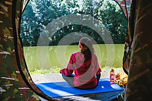 Young woman in the sport wear outfit is sitting and relaxing in the camping in the forest