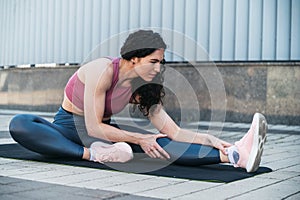 Young woman in sport wear stretching legs before going for jog