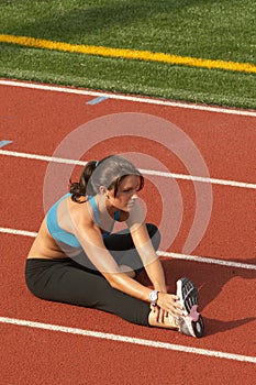 Young Woman in Sports Bra Stretching Hamstring on Track