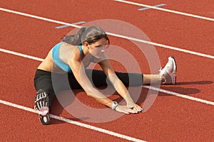 Young Woman in Sports Bra Stretching Legs on Track
