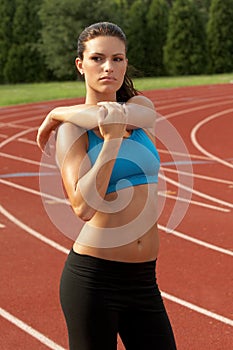 Young Woman in Sports Bra Stretching Triceps Muscle