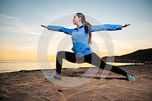 Young woman in sports clothes doing yoga on the beach. Sunset and ocean in the background. Wellness and sports lifestyle