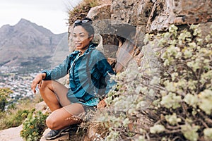 Young woman in sports clothes relaxing during mountain hike looking way, leaning rock