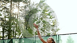 Young woman in sports uniform is playing tennis on an outdoor tennis court