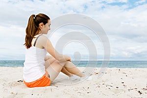 Young woman in sports wear sitting at the beach