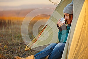 Young woman in sports wear and trekking shoes sitting in bivouac