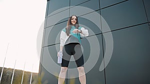 Young woman in sportswear with a bottle look at smart watch while jogging at city public park