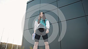 Young woman in sportswear with a bottle look at smart watch while jogging at city public park