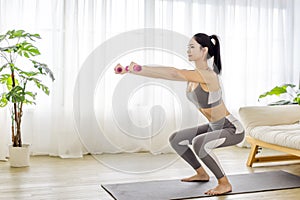 Young woman in sportswear doing fitness stretching exercises at home