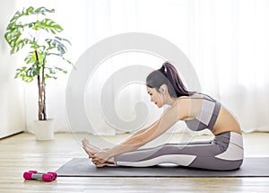 Young woman in sportswear doing fitness stretching exercises at home