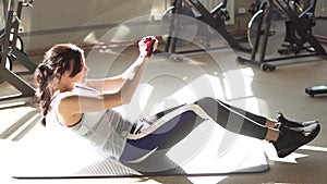 Young woman in sportswear exercising abdominals in gym. attractive girl athlete engaged in exercises on work abdominal