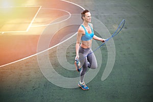 Young woman in sportswear exercising with skipping rope on stadium