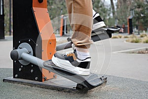 A young woman in sportswear exercising on an training apparatus outdoors in a city park