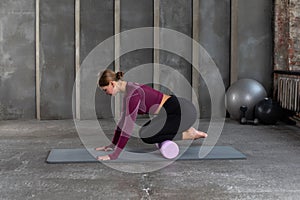 A young woman in sportswear performs a myofascial massage of the lower leg muscles with a roller. Muscle recovery, mfr.